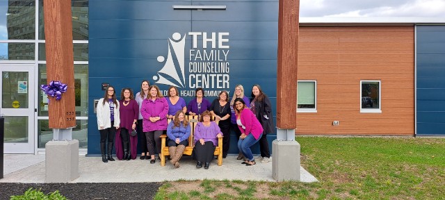 Women stand outside building dressed in purple